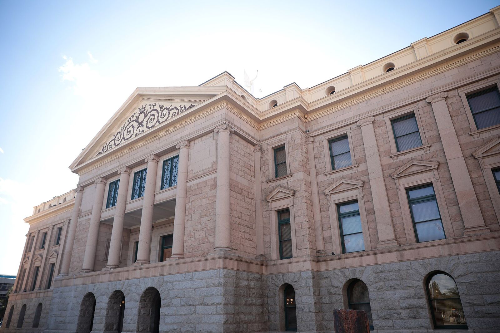 The stone facade of the Arizona State Capitol building in Phoenix against a bright sky