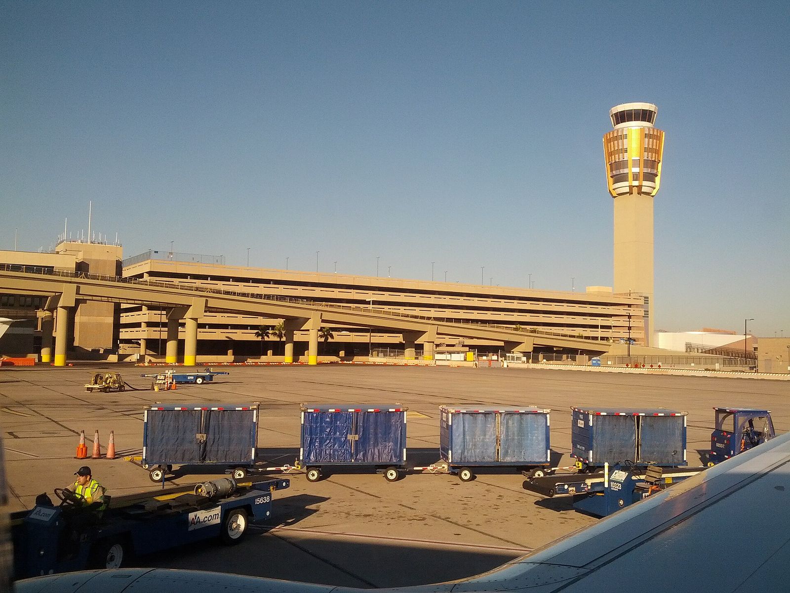 The air traffic control tower at Phoenix Sky Harbor International Airport, with baggage carts on the ramp below