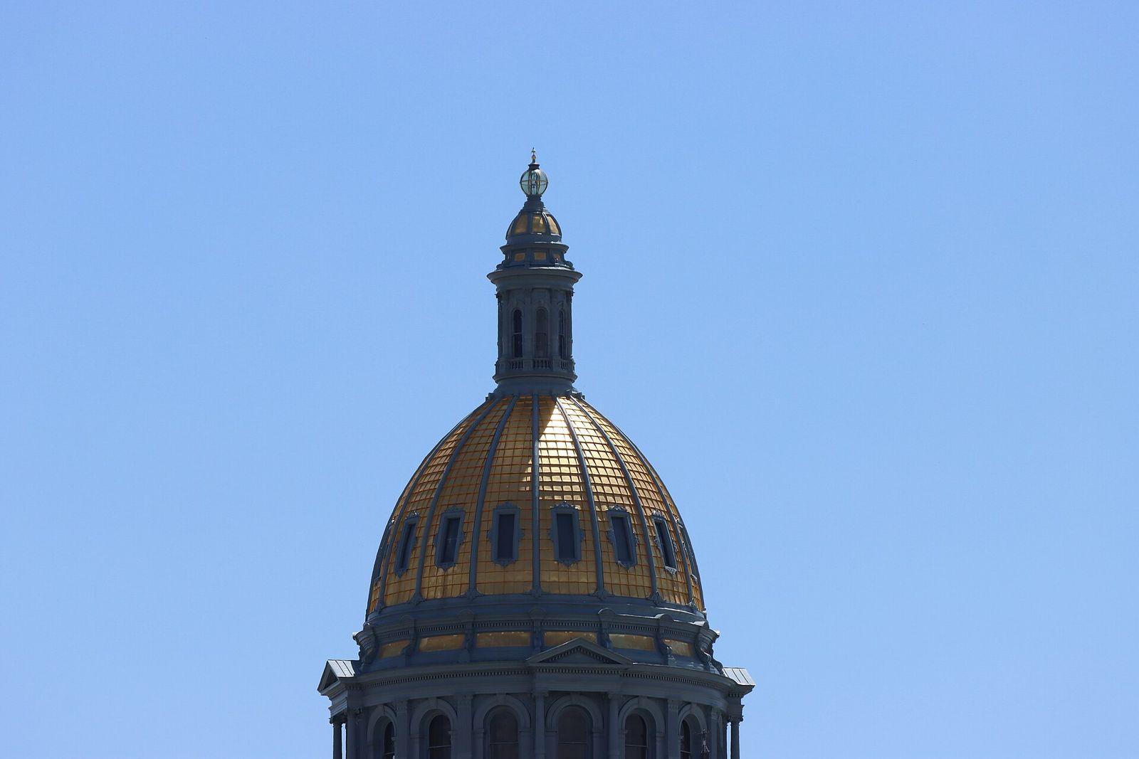 The gold dome of the Colorado State Capitol in Denver against a clear blue sky