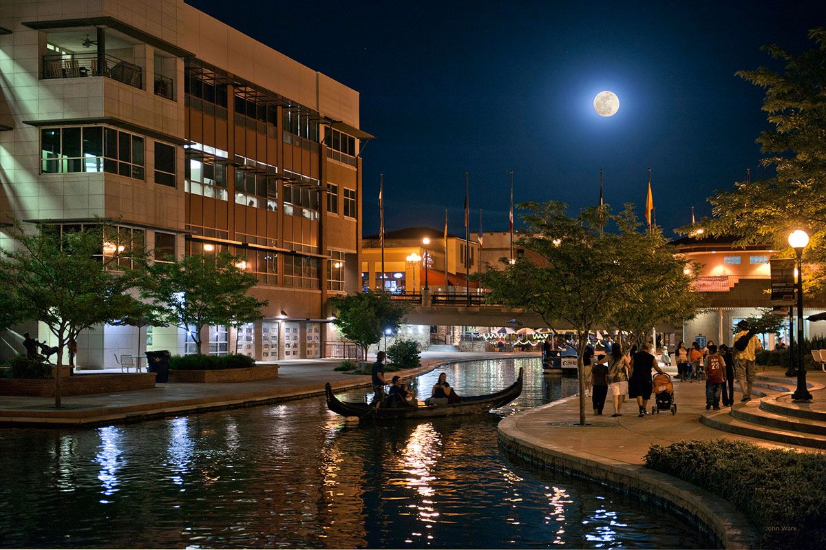 The Historic Arkansas Riverwalk of Pueblo lit up at night under a full moon