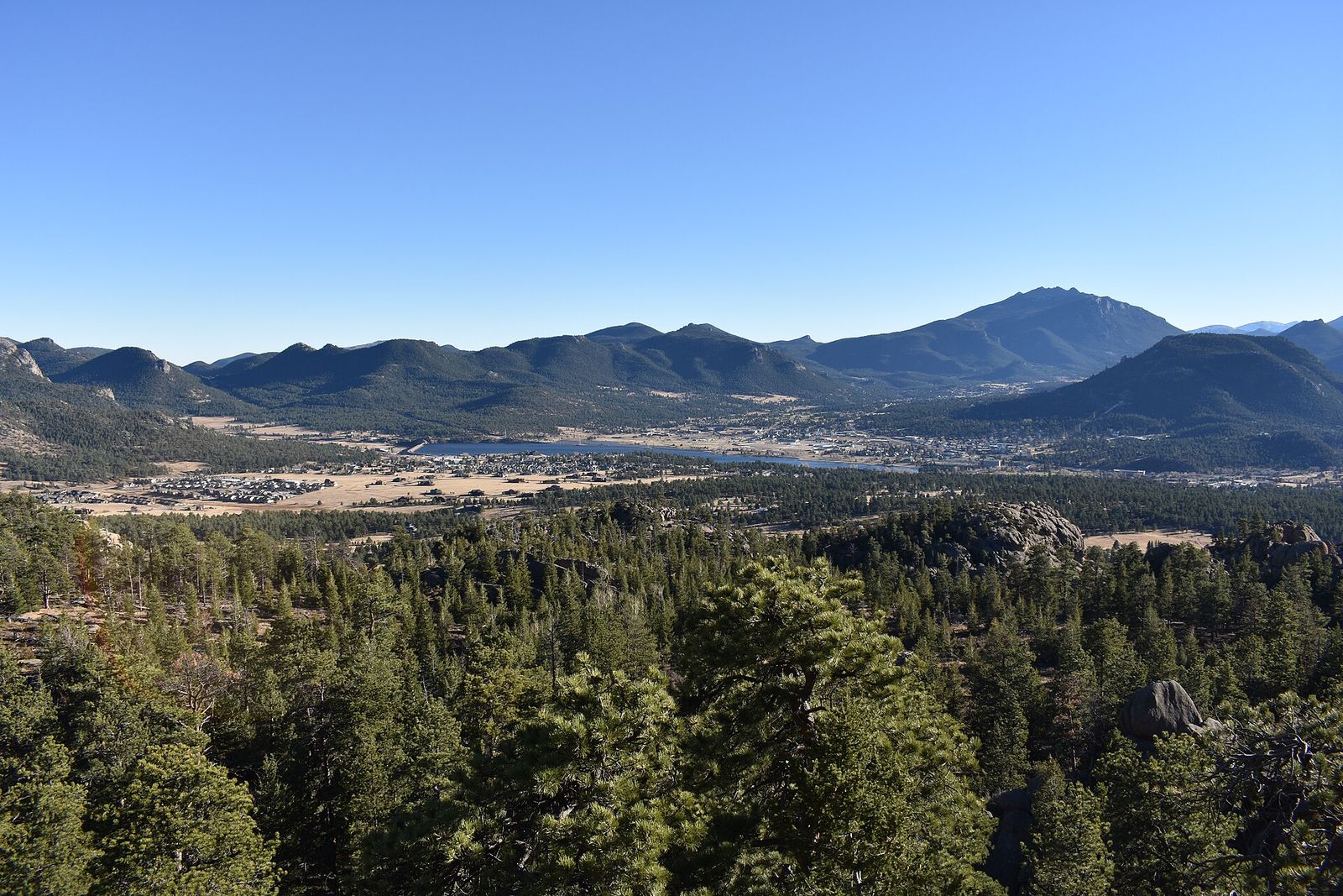 Estes Park and its ring of mountains seen from the Gem Lake Trail, with pine forest below