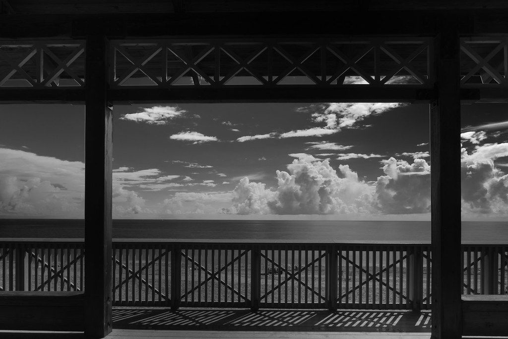 A black and white view of the ocean through the South Beach Park pavilion railings