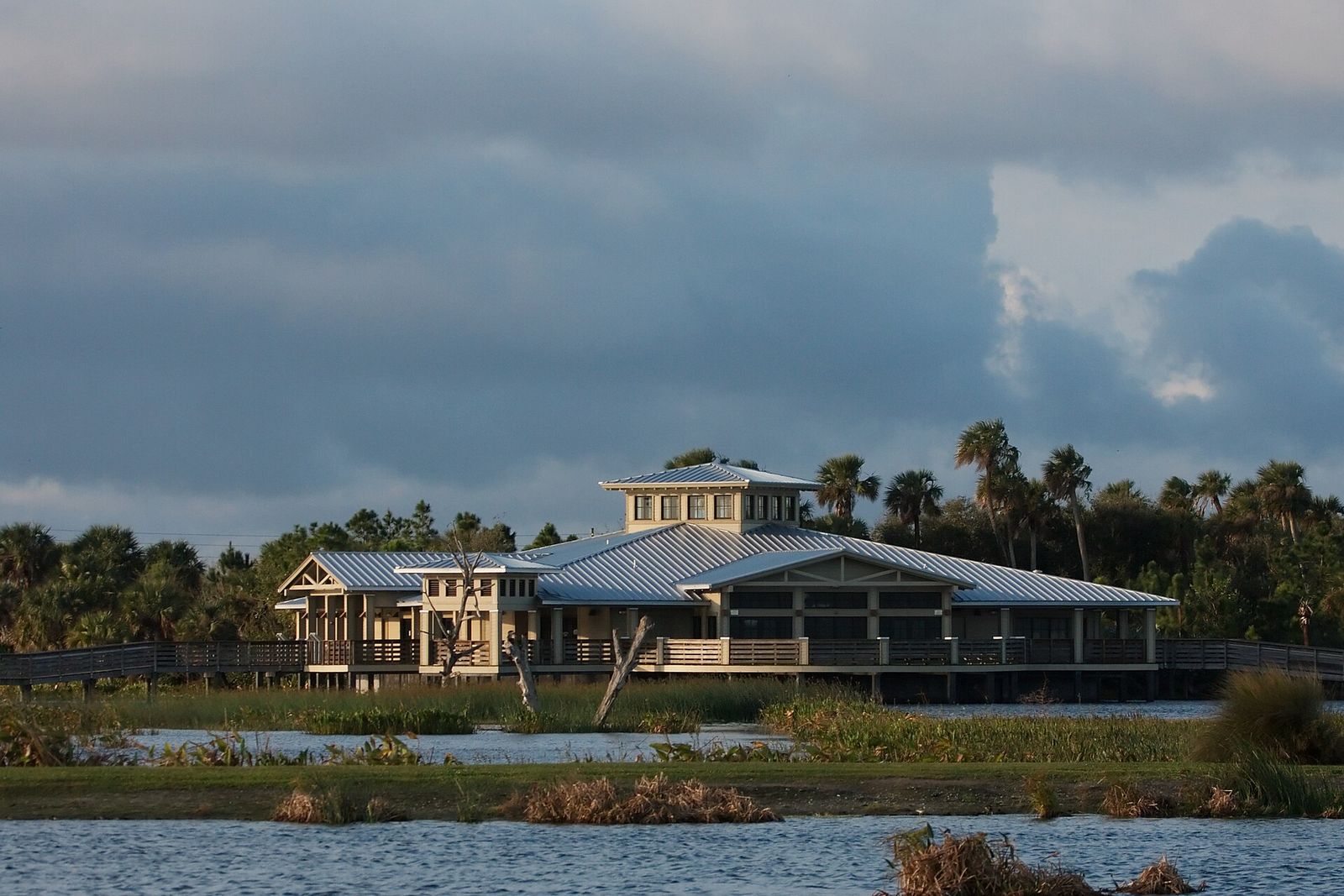 The Green Cay Nature Center building with its broad metal roof, seen across the wetland water under a gray sky