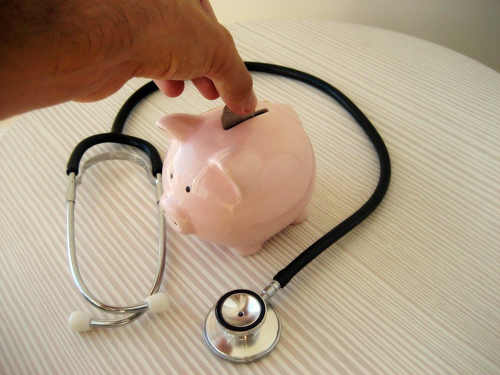 A stethoscope wrapped around a piggy bank