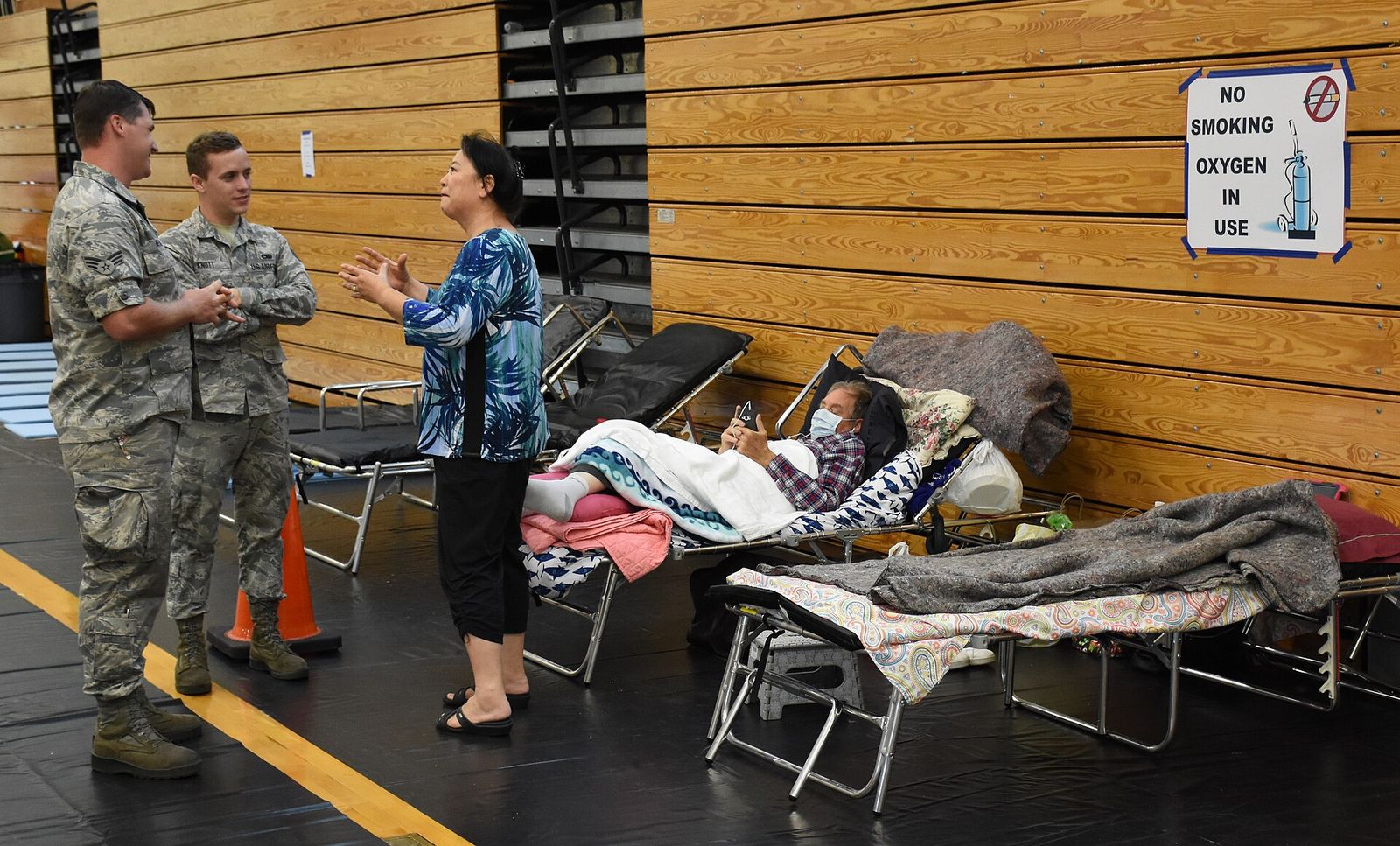 Cots set up in a Florida school shelter with guardsmen talking to an evacuee