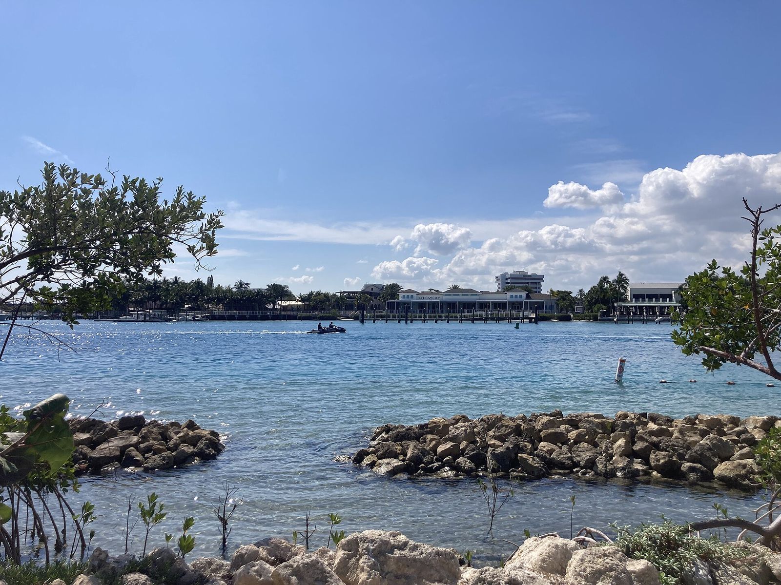Boats on the blue Jupiter Inlet beyond a rock jetty, seen from the nature trail at the Jupiter Inlet Lighthouse