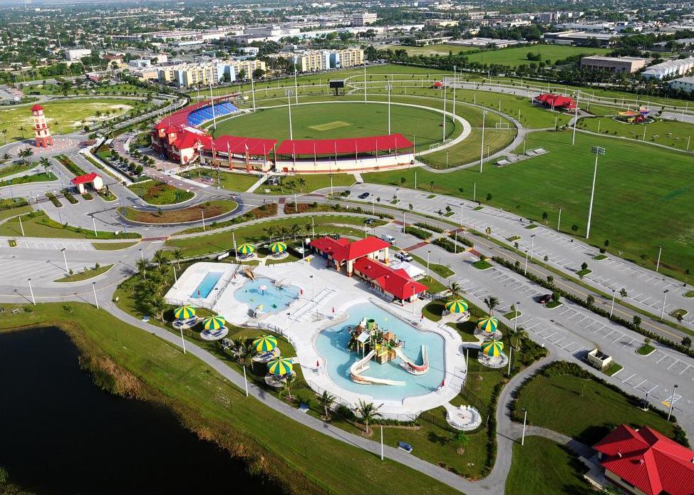 A drone view of Lauderhill's aquatics center with its pools and slides beside Broward County Stadium and its cricket field