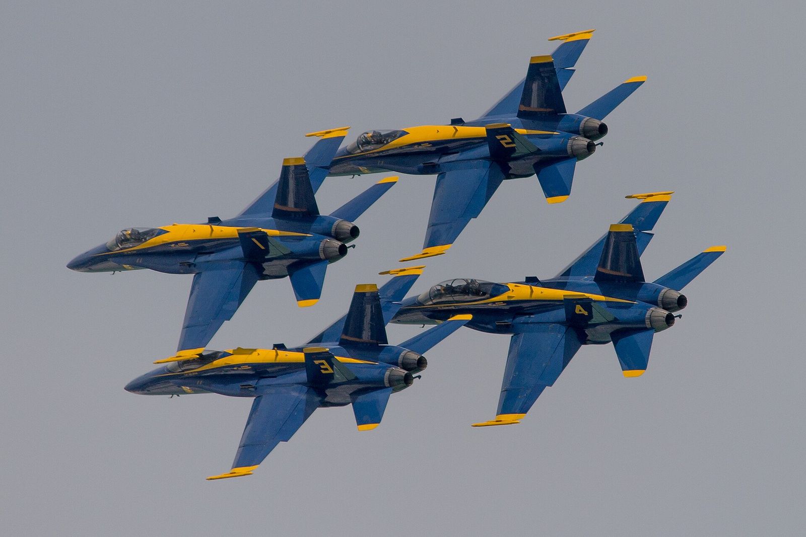 Four Blue Angels jets flying in tight formation over Pensacola Beach