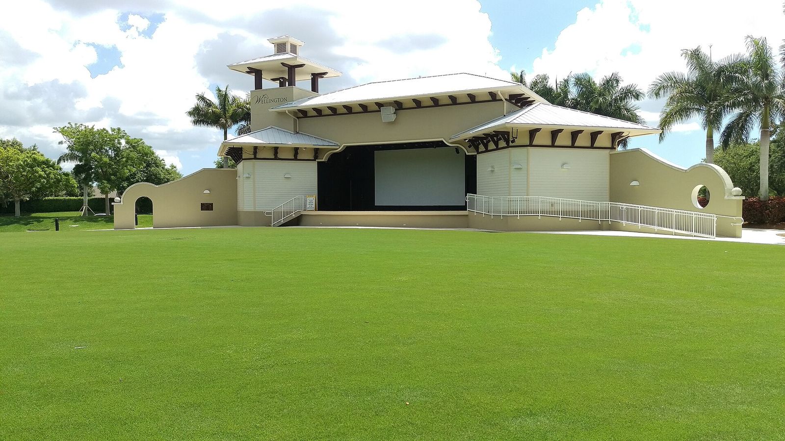 The cream-colored Wellington Amphitheater stage with two tiled towers behind a wide, freshly cut lawn