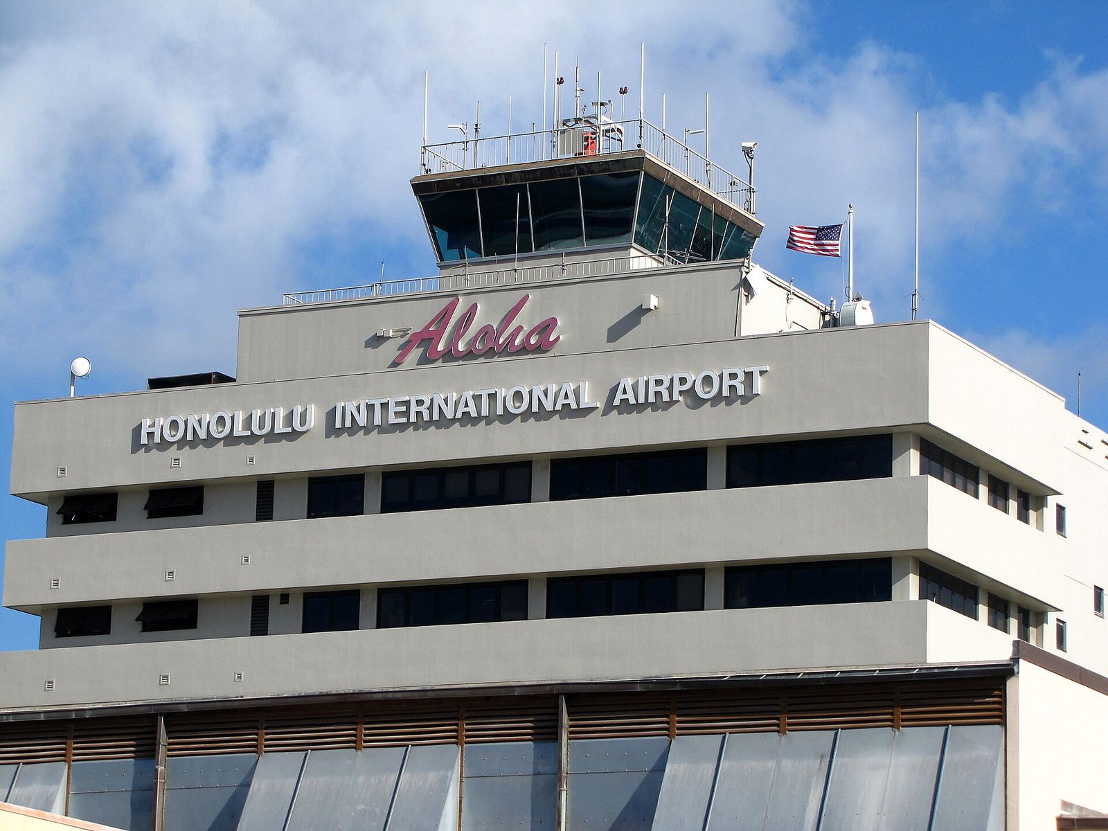 The control tower building at the Honolulu airport with an Aloha sign and the words Honolulu International Airport