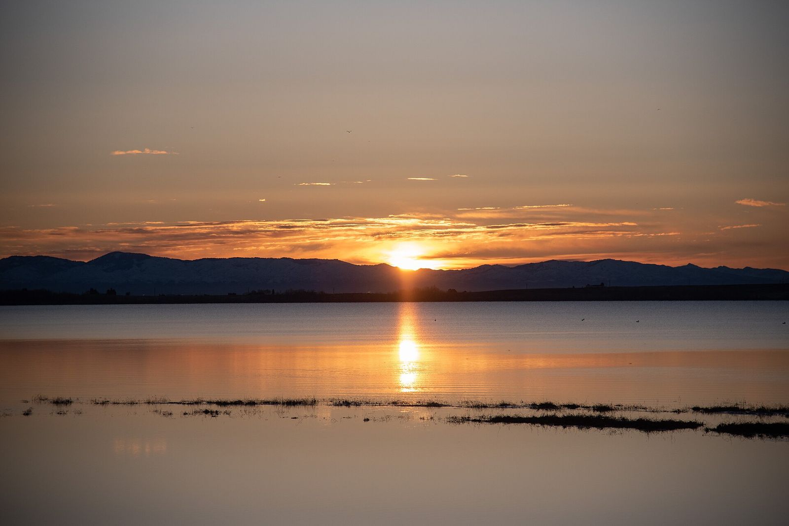 The sun rising over Lake Lowell at Deer Flat National Wildlife Refuge in Canyon County, reflected in the calm water