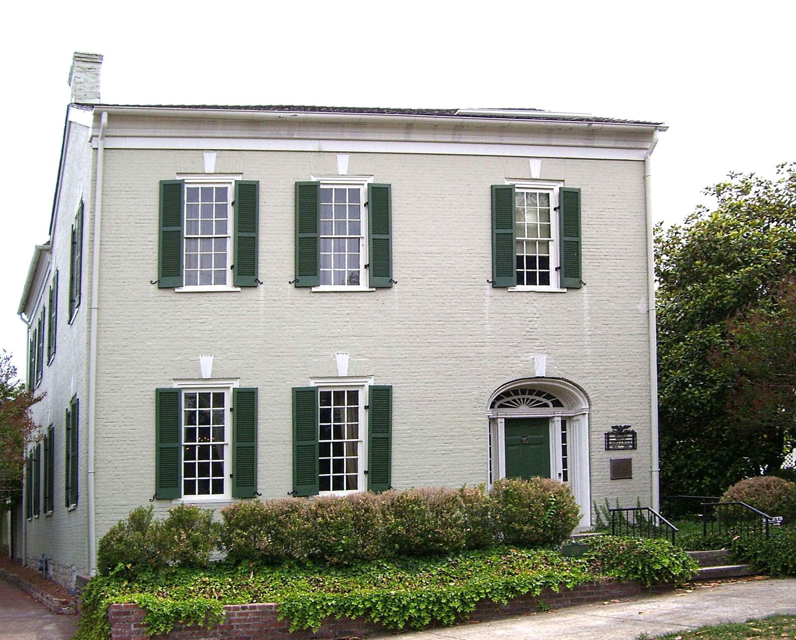 The two-story white James K. Polk Home with green shutters in Columbia