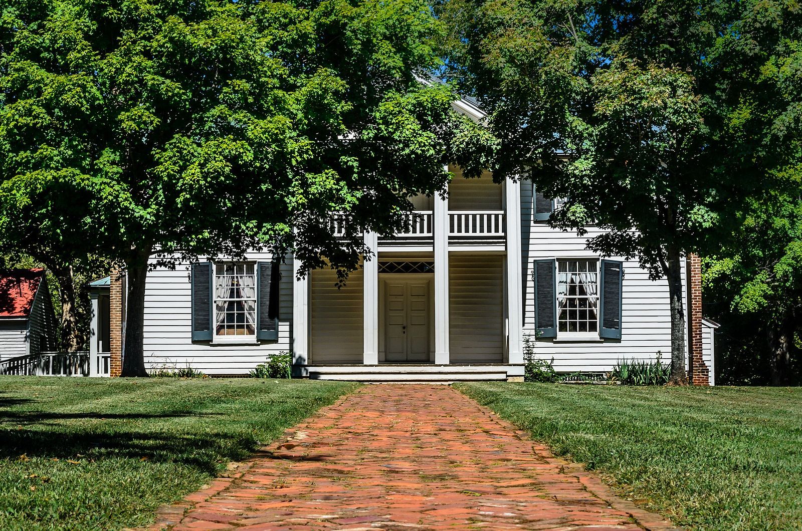 The white two-story Sam Davis House behind a brick walkway in Smyrna