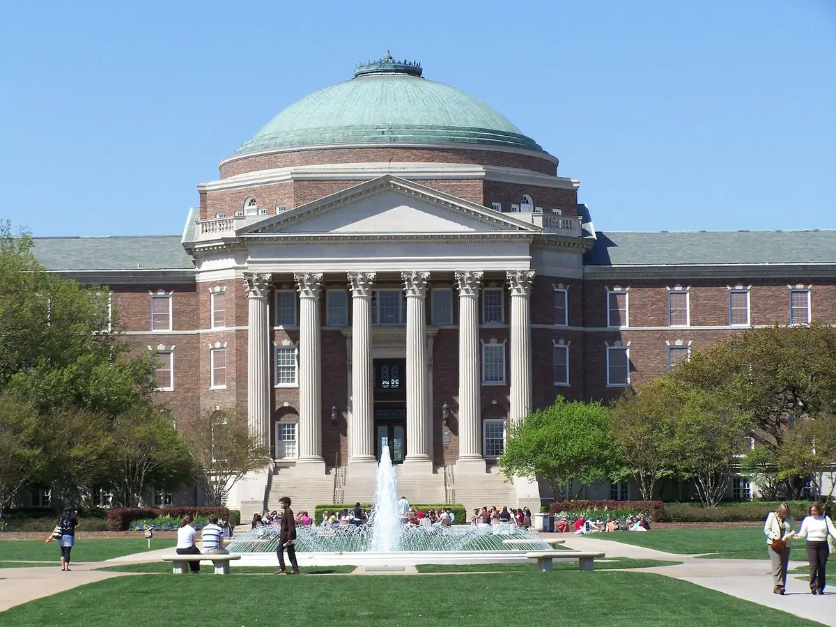 Dallas Hall, the domed main building of Southern Methodist University, with students on the lawn and a fountain in front