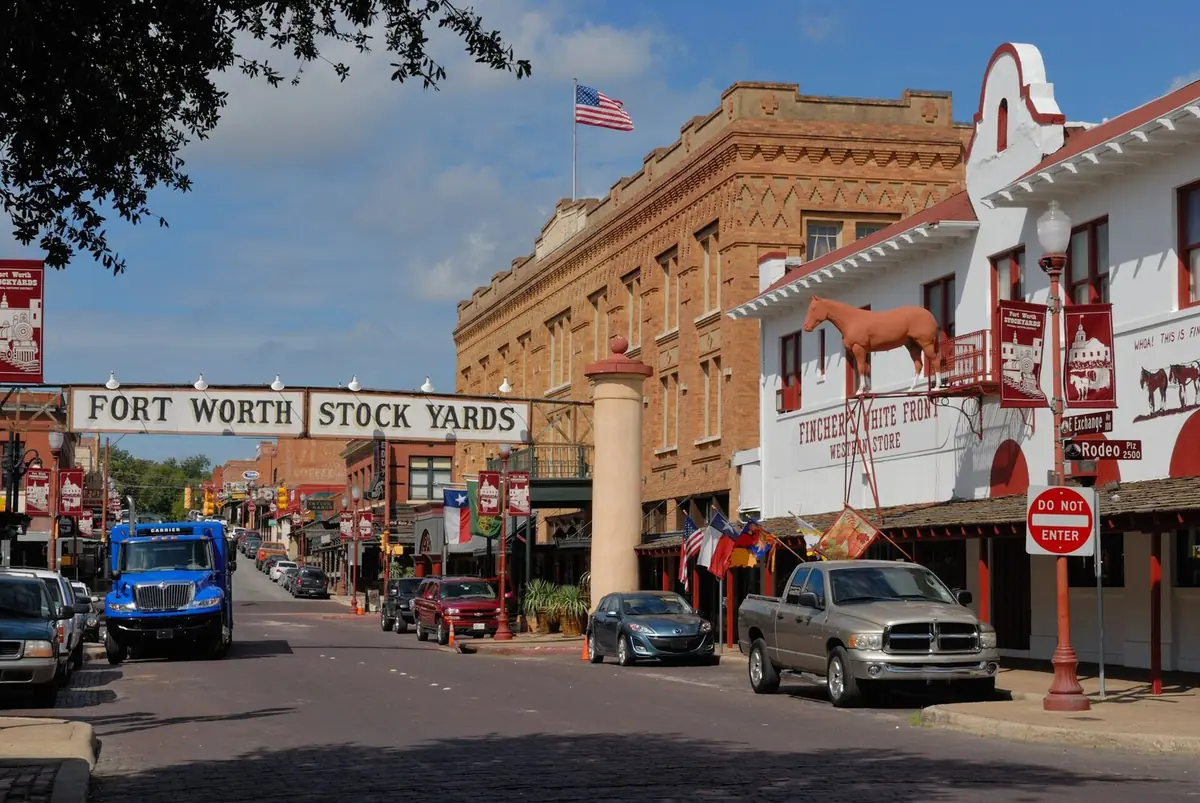 Exchange Avenue in the Fort Worth Stockyards under the arched Fort Worth Stock Yards sign, with brick storefronts on both sides