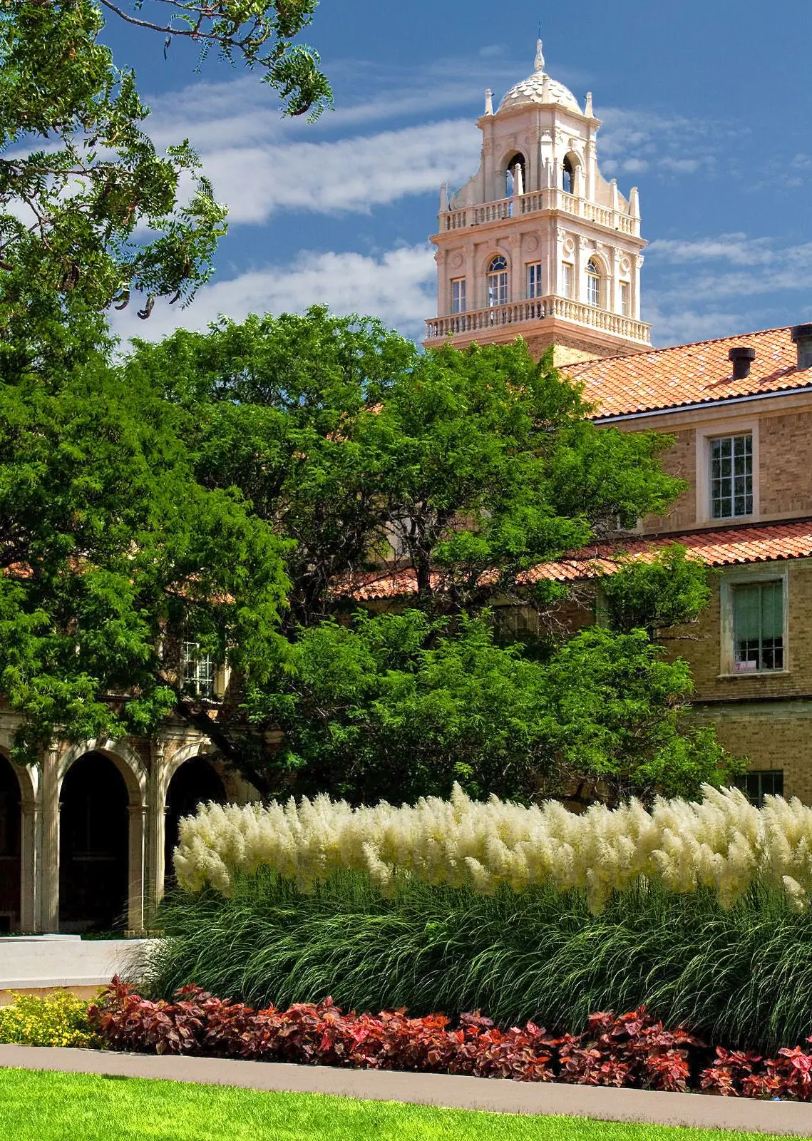A tower of the Administration Building at Texas Tech University in Lubbock, framed by trees and flower beds