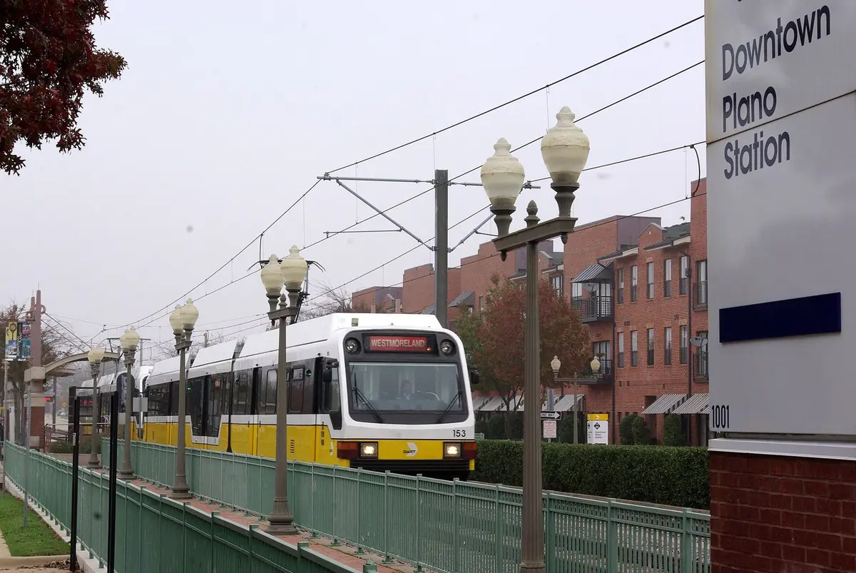 A DART Red Line train leaving Downtown Plano Station beside the station sign