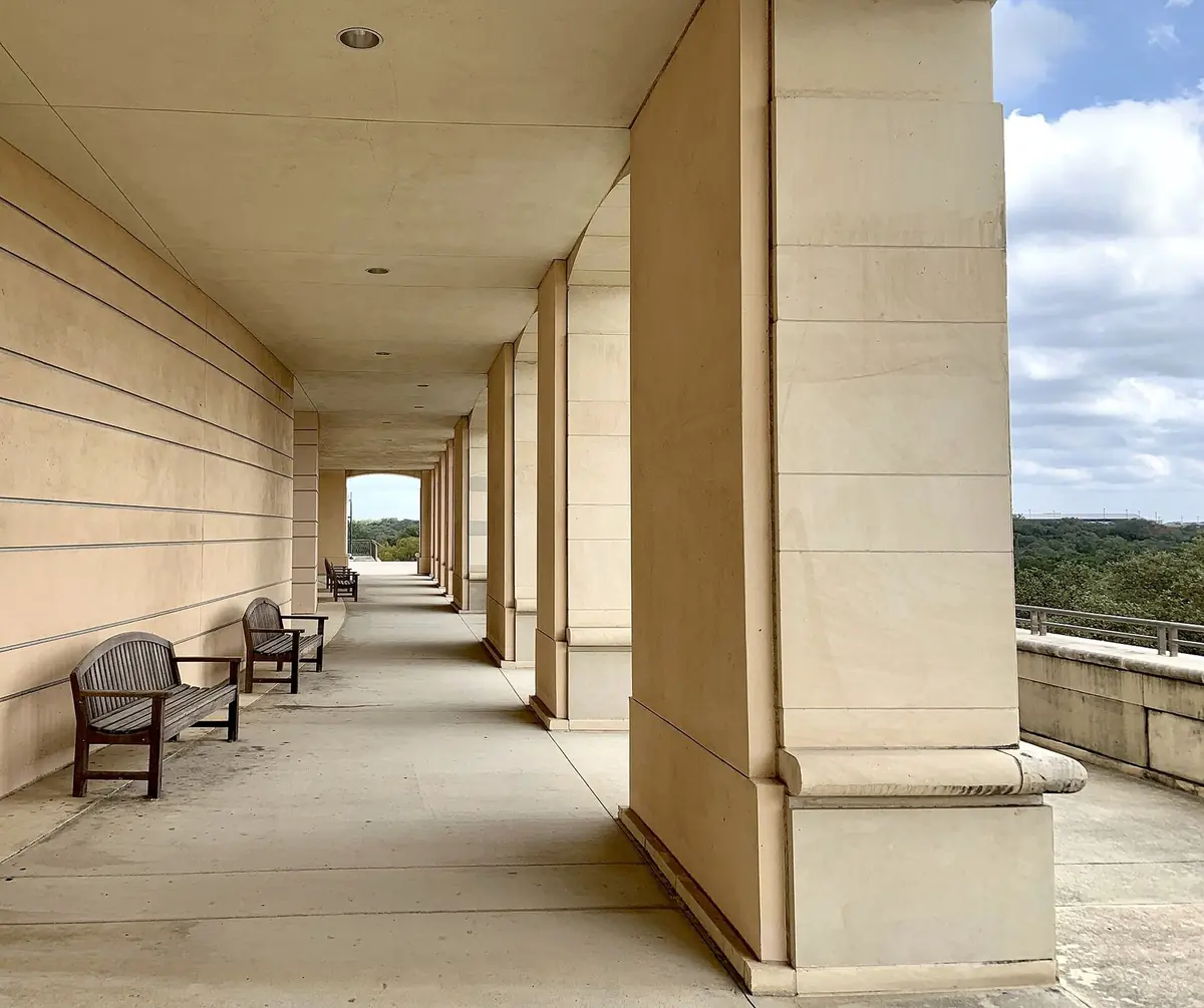 A shaded colonnade with benches along the UTSA Main Building, looking out over the west side of the Main Campus