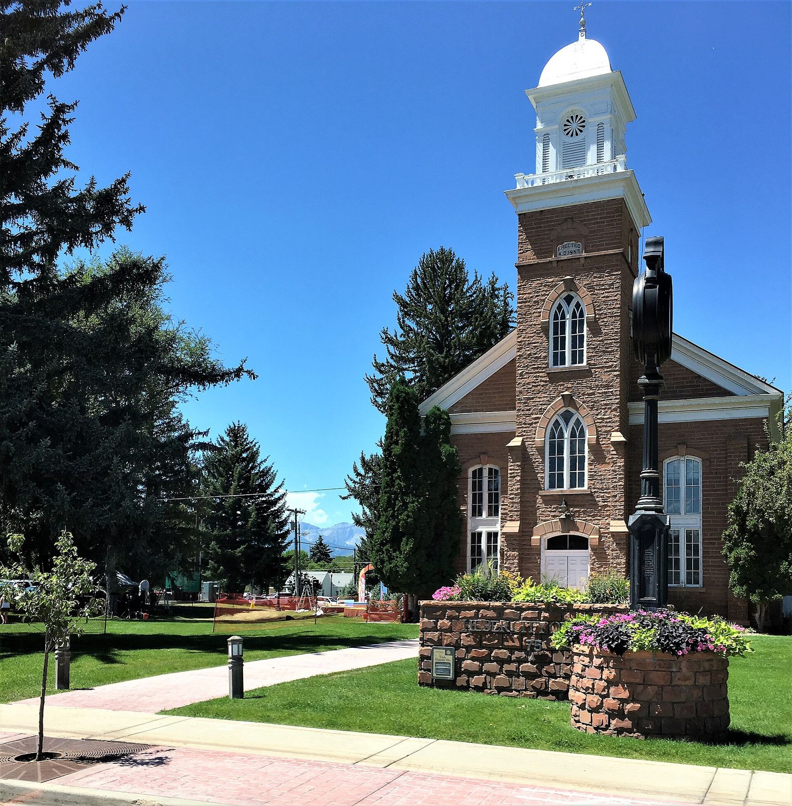 The red stone Wasatch Stake Tabernacle in Heber City, with its white clock tower and flower beds in front