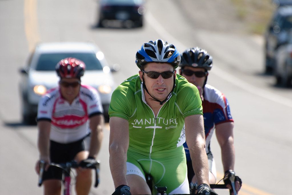 Three road cyclists in racing kit riding through a stop during a bike race in Highland