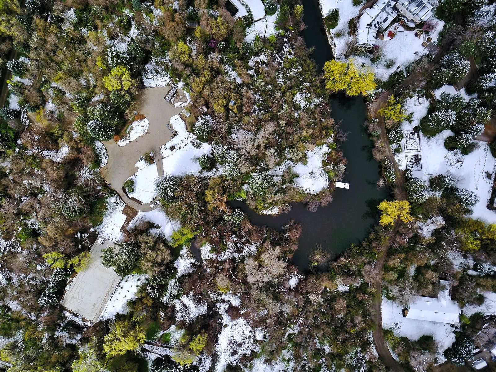 An aerial view over Holladay of tree-shaded yards, a winding pond and patches of snow