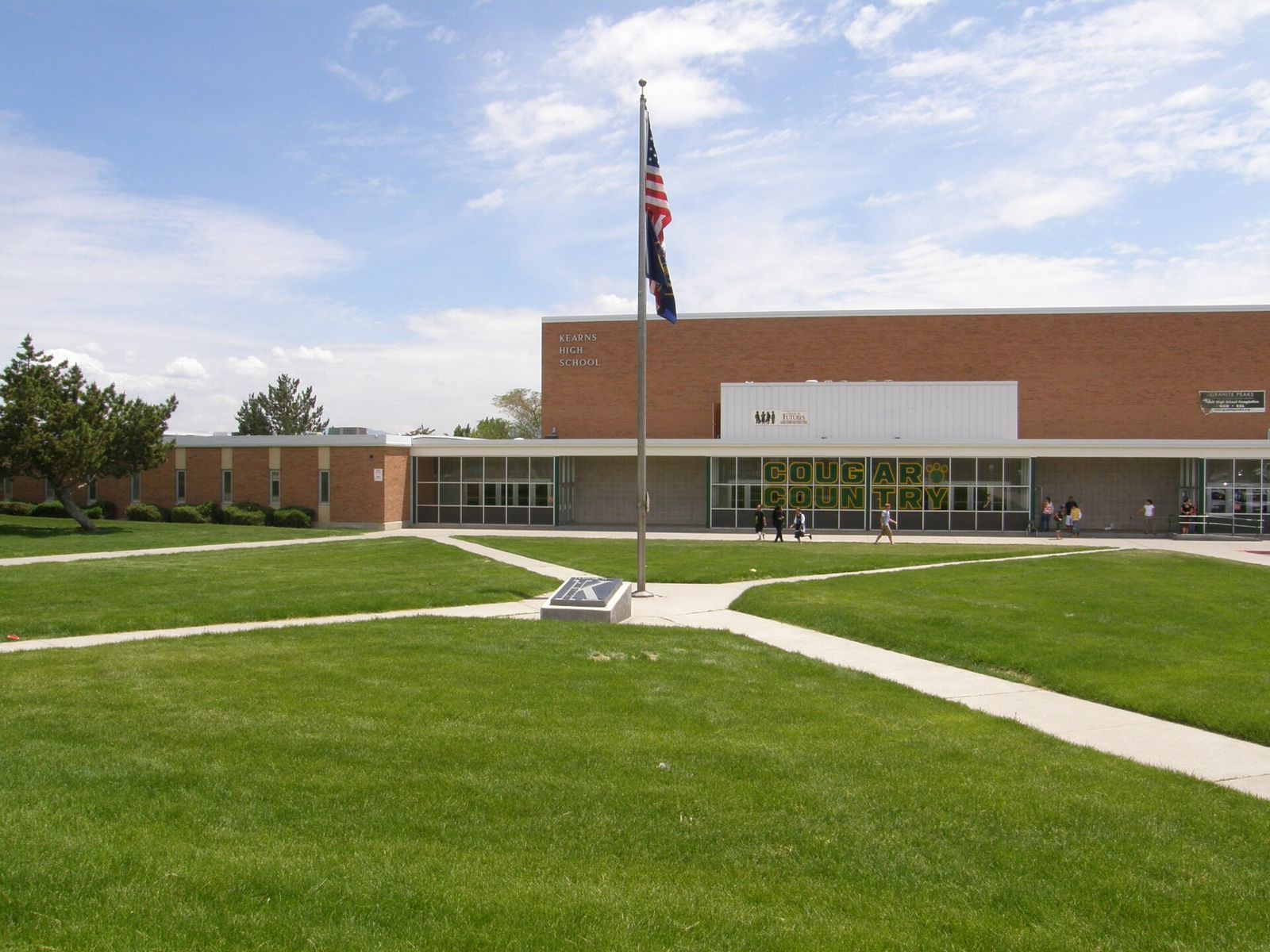 The front of Kearns High School with a flagpole and lawn