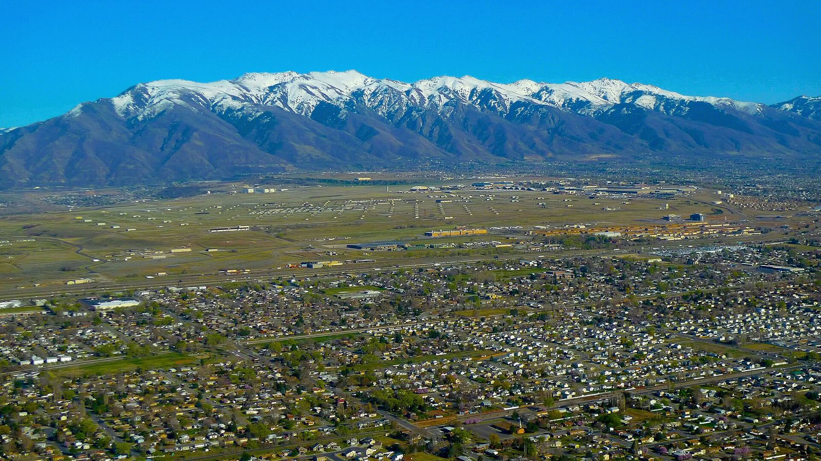 Homes spread across the valley floor below the snow-capped Wasatch Mountains near Hill Air Force Base