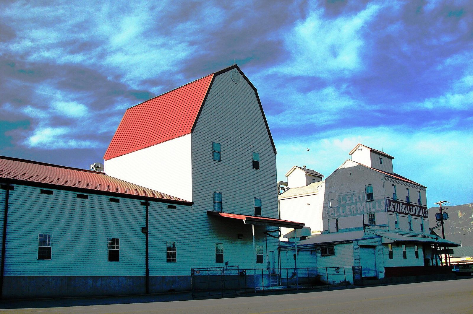The white Lehi Roller Mills buildings with a red roof under a dramatic sky