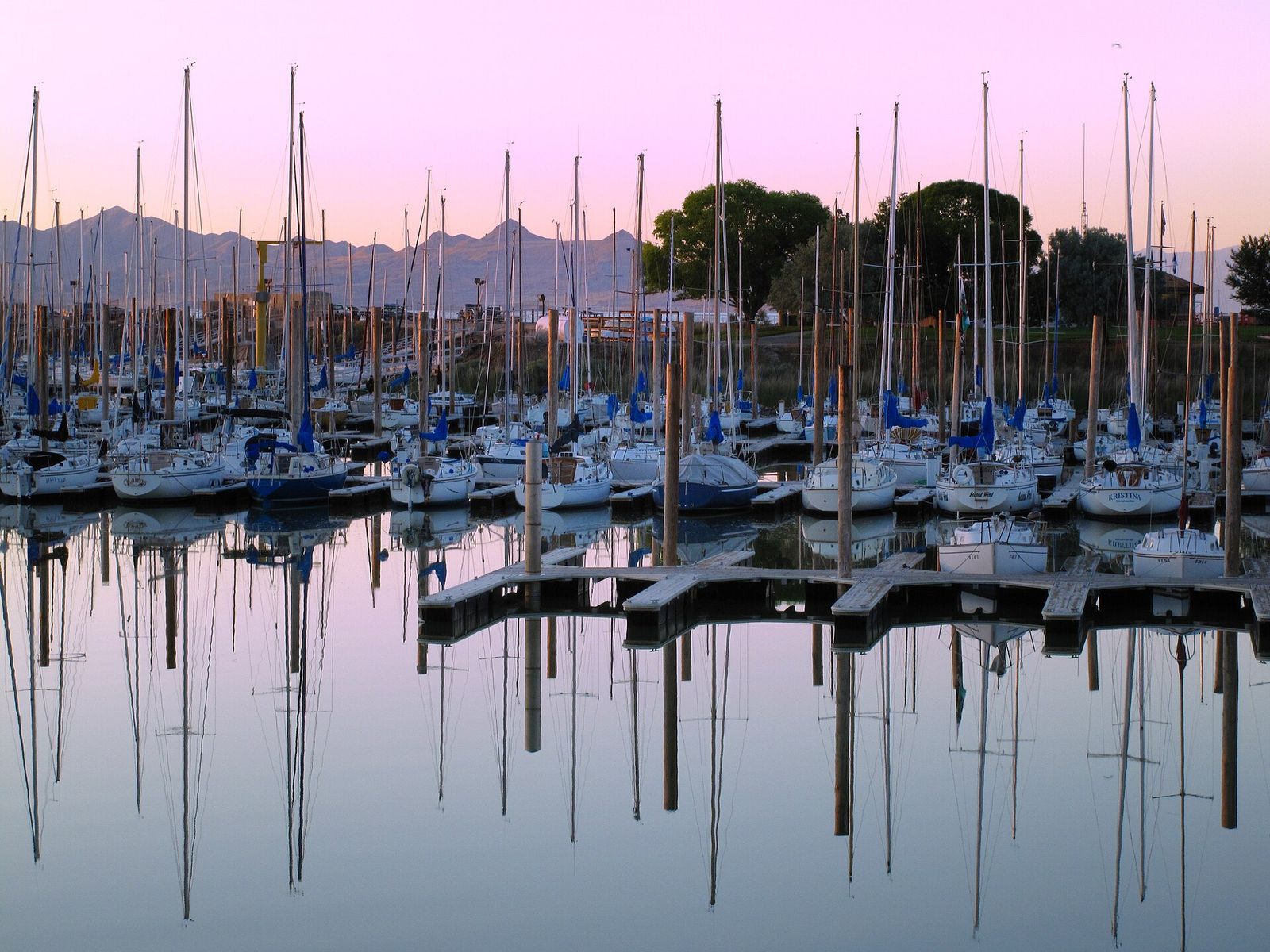 Sailboat masts reflected in still water at the Great Salt Lake marina at dusk