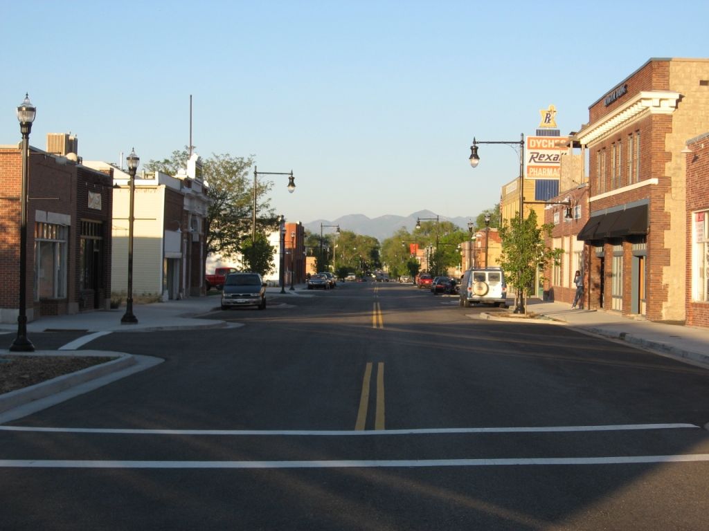 Brick storefronts and old street lamps lining historic Main Street in Magna, with mountains in the distance