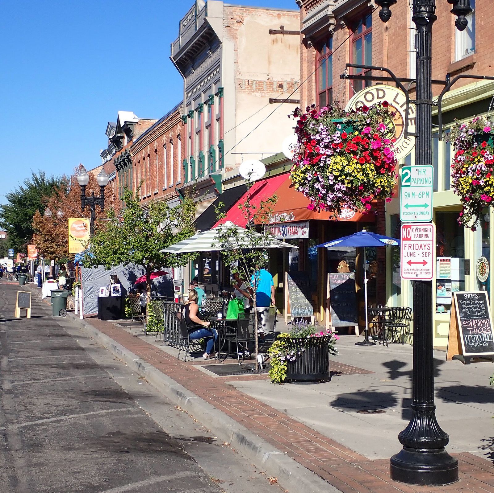Shoppers and hanging flower baskets along the farmers market on Historic 25th Street