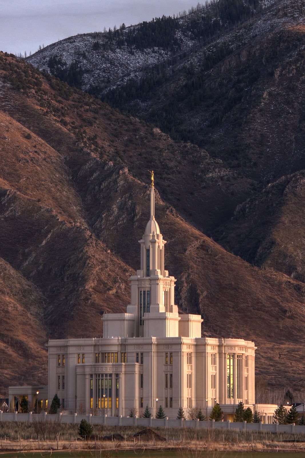 The white Payson Utah Temple with its single spire, below brown mountain slopes