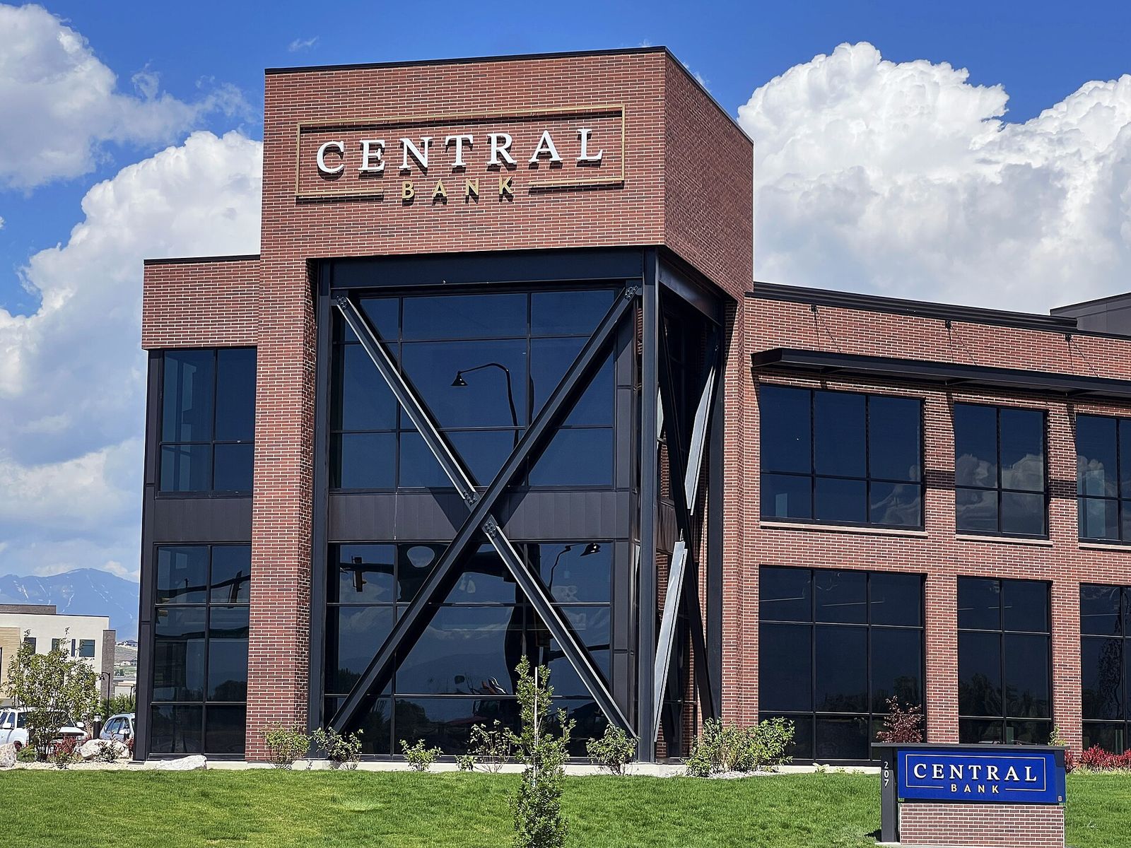 A modern brick and glass Central Bank building in Saratoga Springs under a summer sky