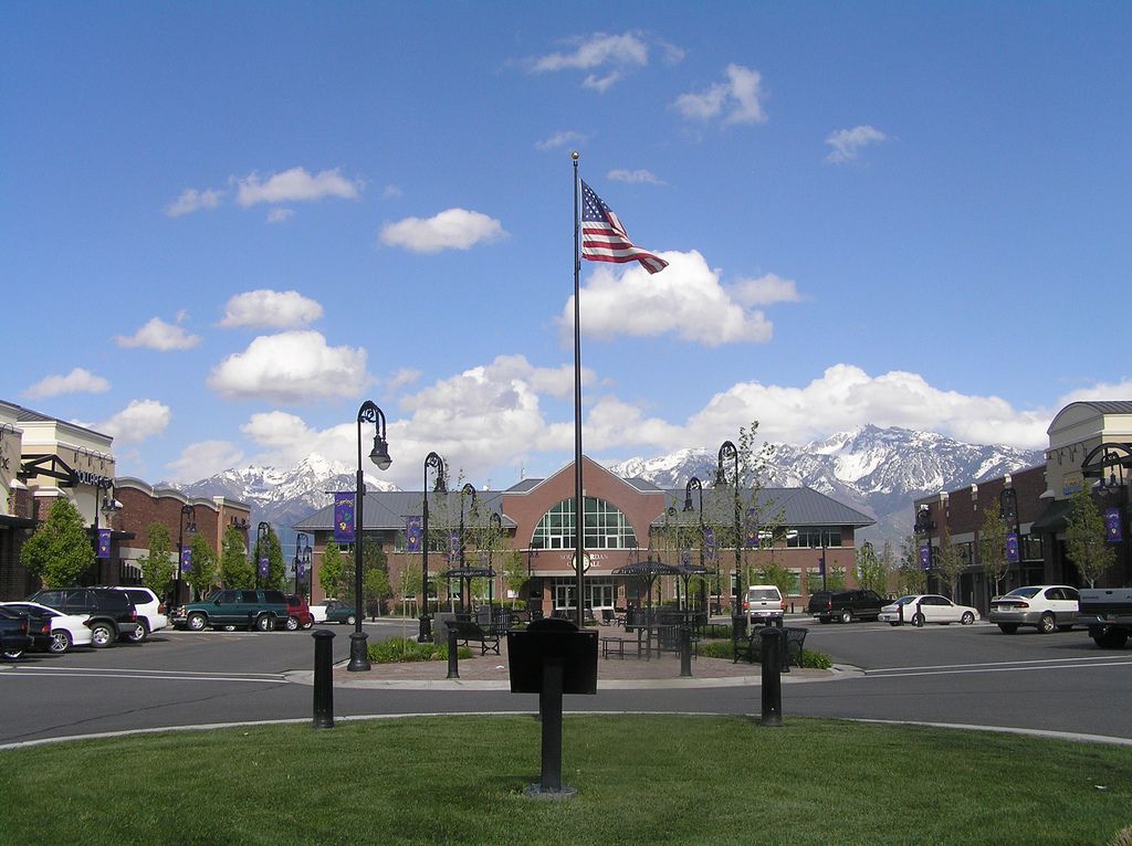 South Jordan City Hall at Towne Center, with flags out front and snow on the mountains behind
