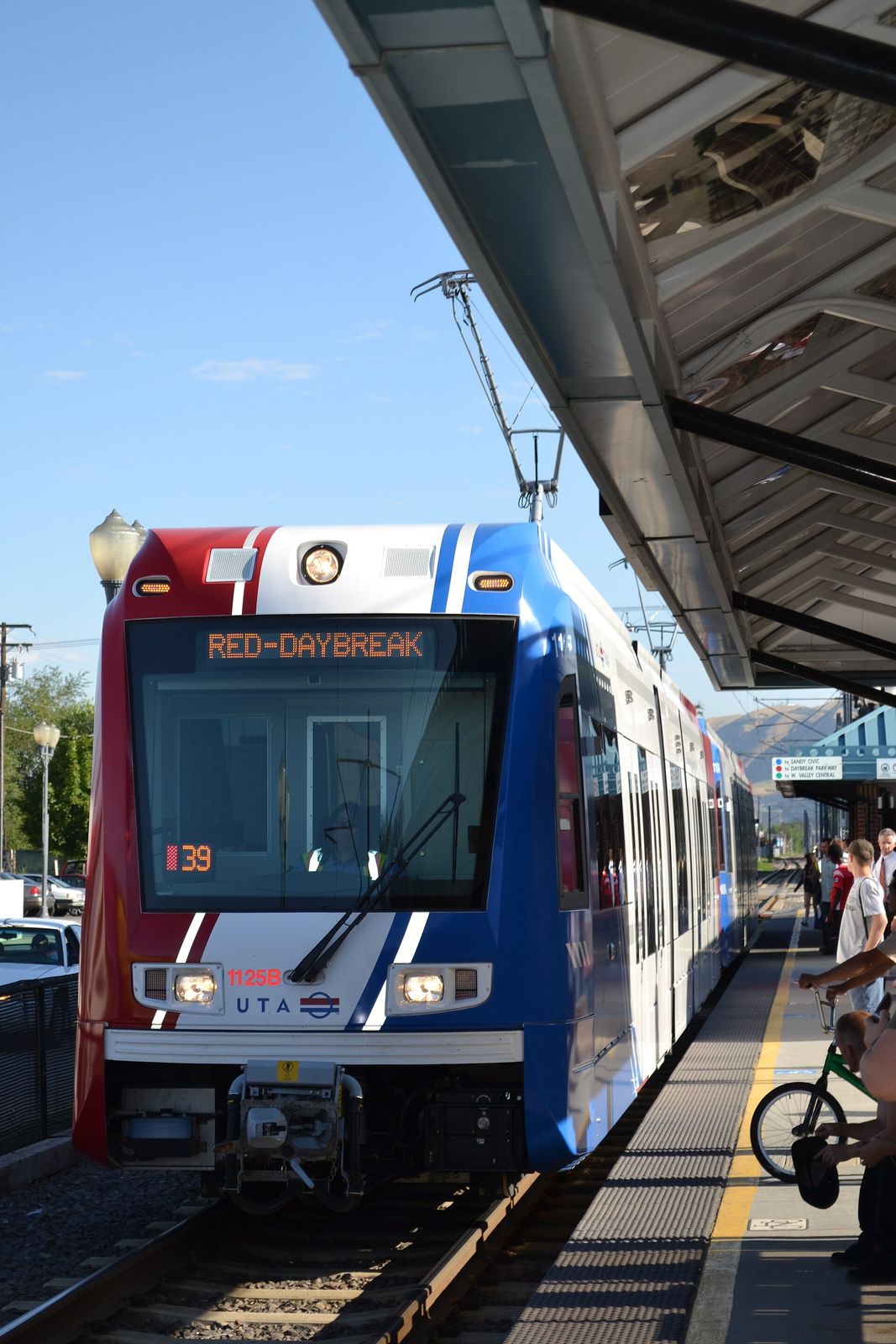A red, white and blue TRAX light rail train beside the platform at Central Pointe station