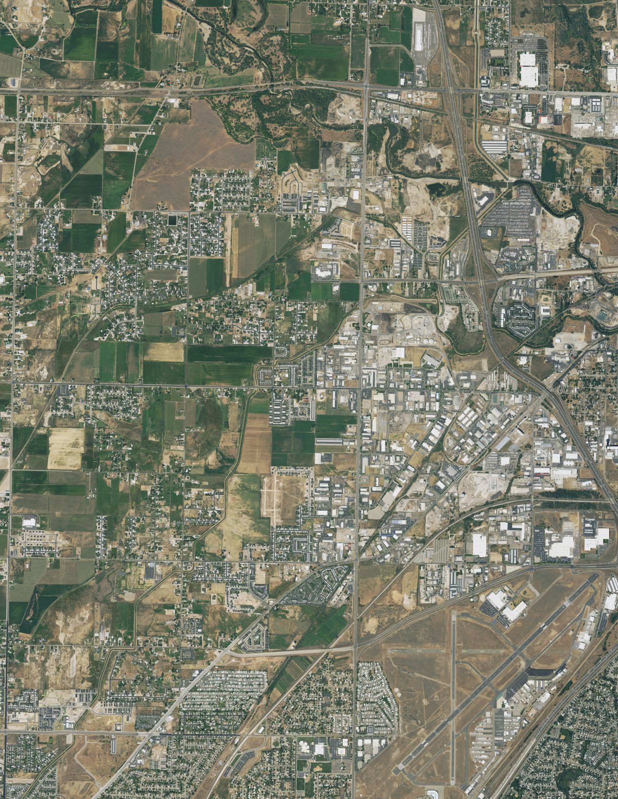 A 2021 aerial image of fields, subdivisions and the river corridors around the Weber and Ogden river confluence