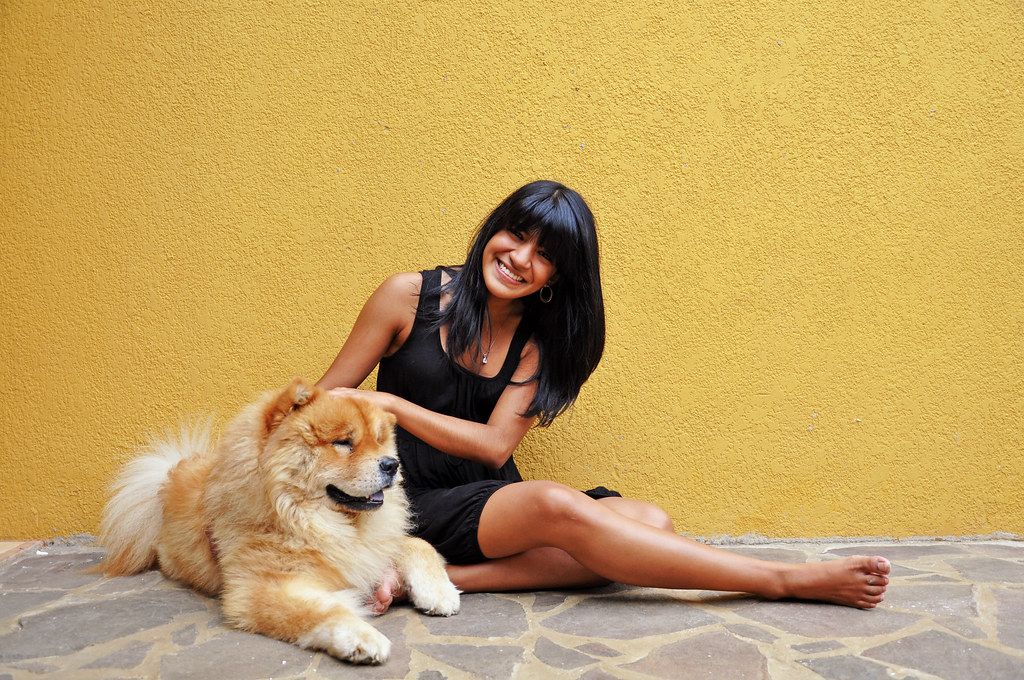 Smiling woman sitting on the ground beside her fluffy dog