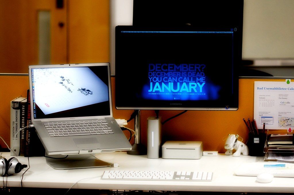 Home office desk with a laptop and a monitor displaying a January calendar