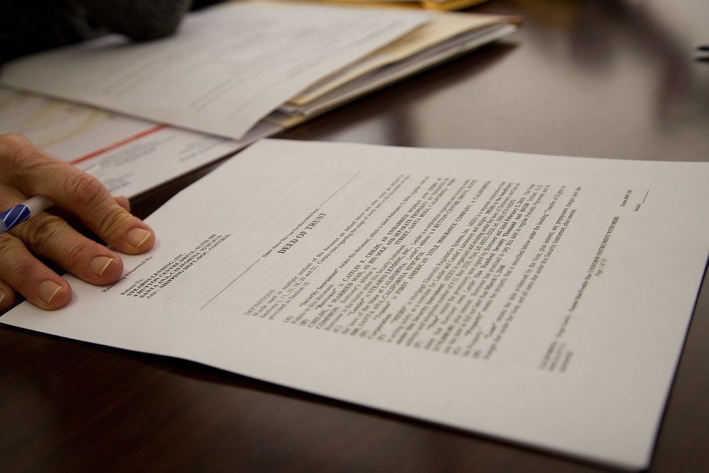 Hands resting on a stack of printed documents being reviewed at a desk