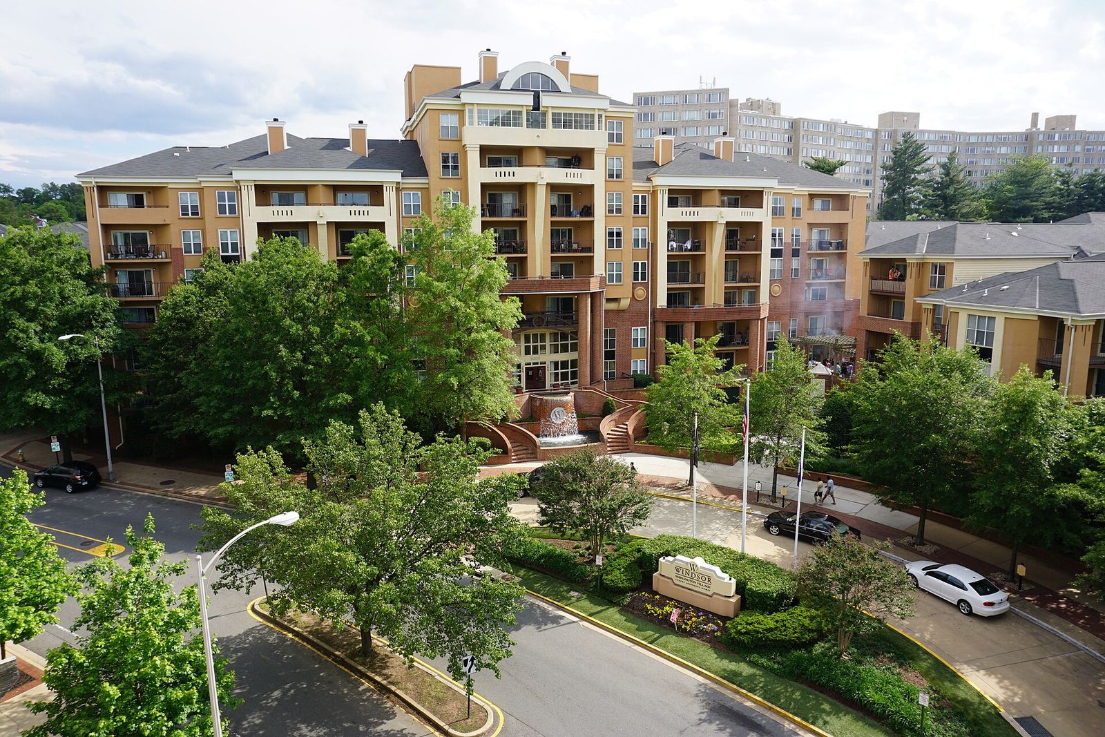 Windsor at Shirlington Village, a mid-rise apartment complex with balconies above a tree-lined circular drive in Arlington, Virginia