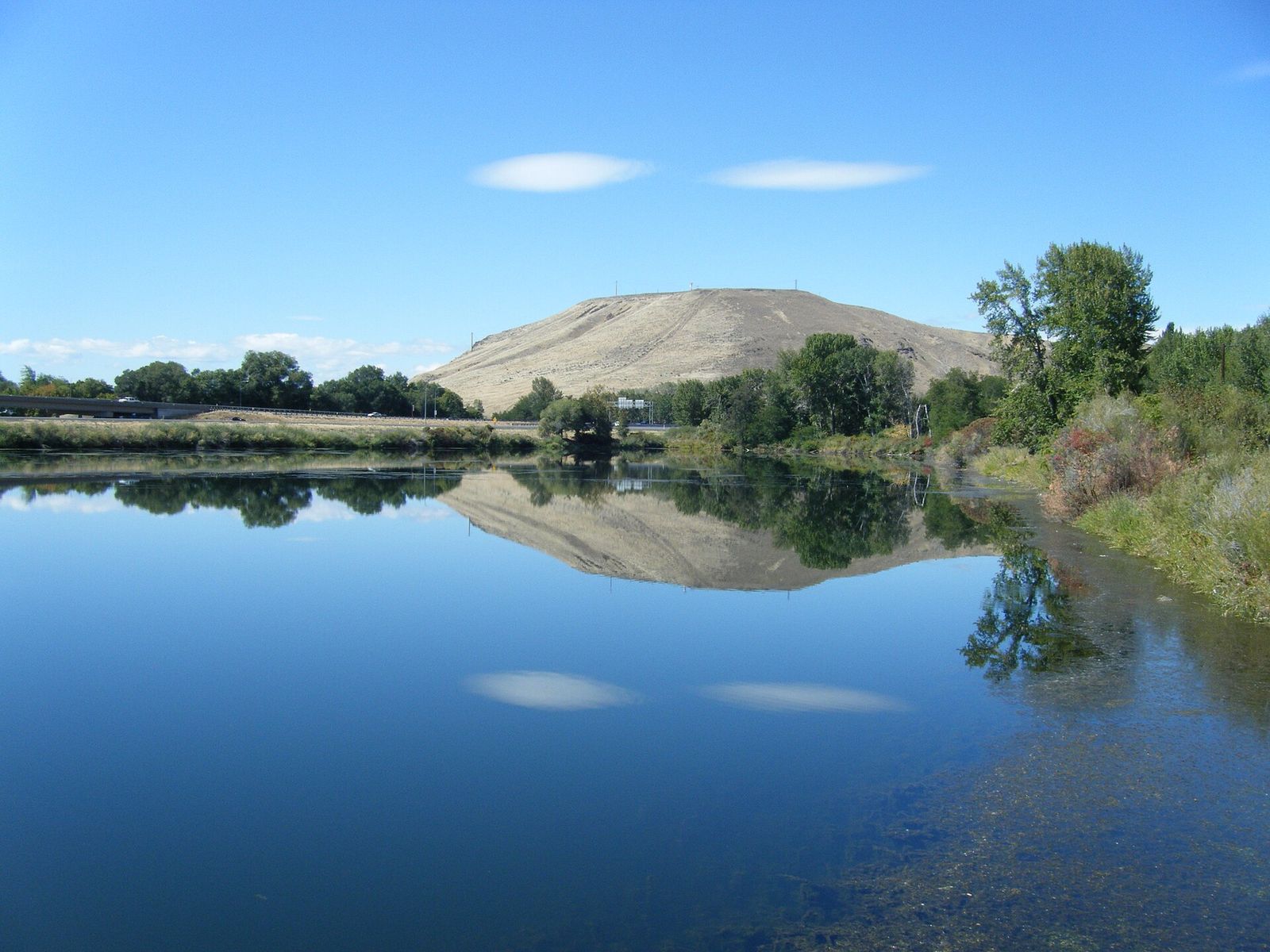 A calm pond on the Yakima Greenway reflecting a nearby hill